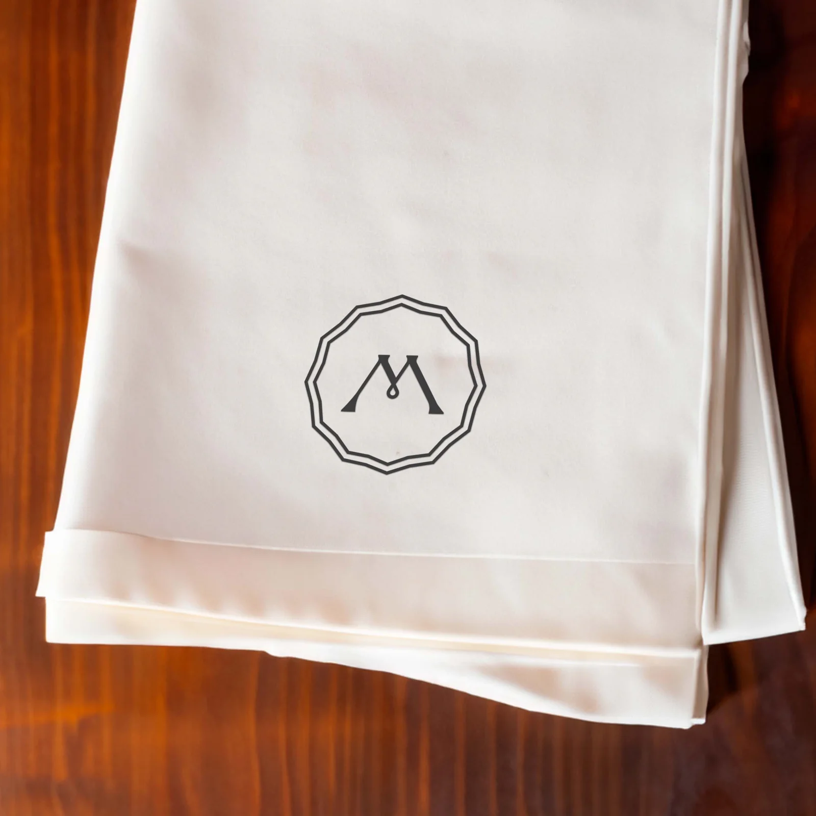 Folded ivory napkin with the Madera seal on a dark wooden table